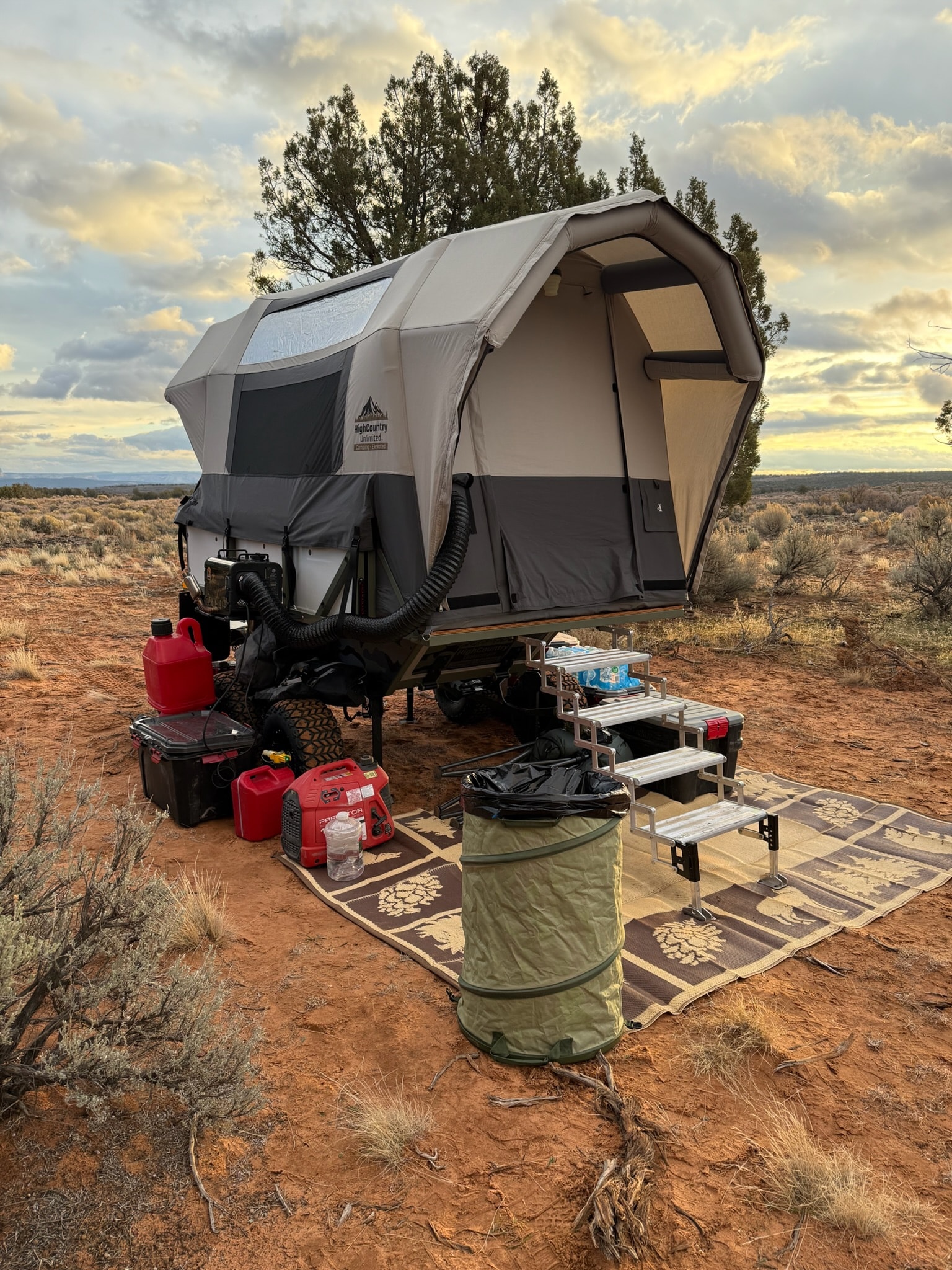 A High Country Unlimited Conestoga Rover covered wagon camper with its arched airframe tent deployed at a high-desert camp at dusk