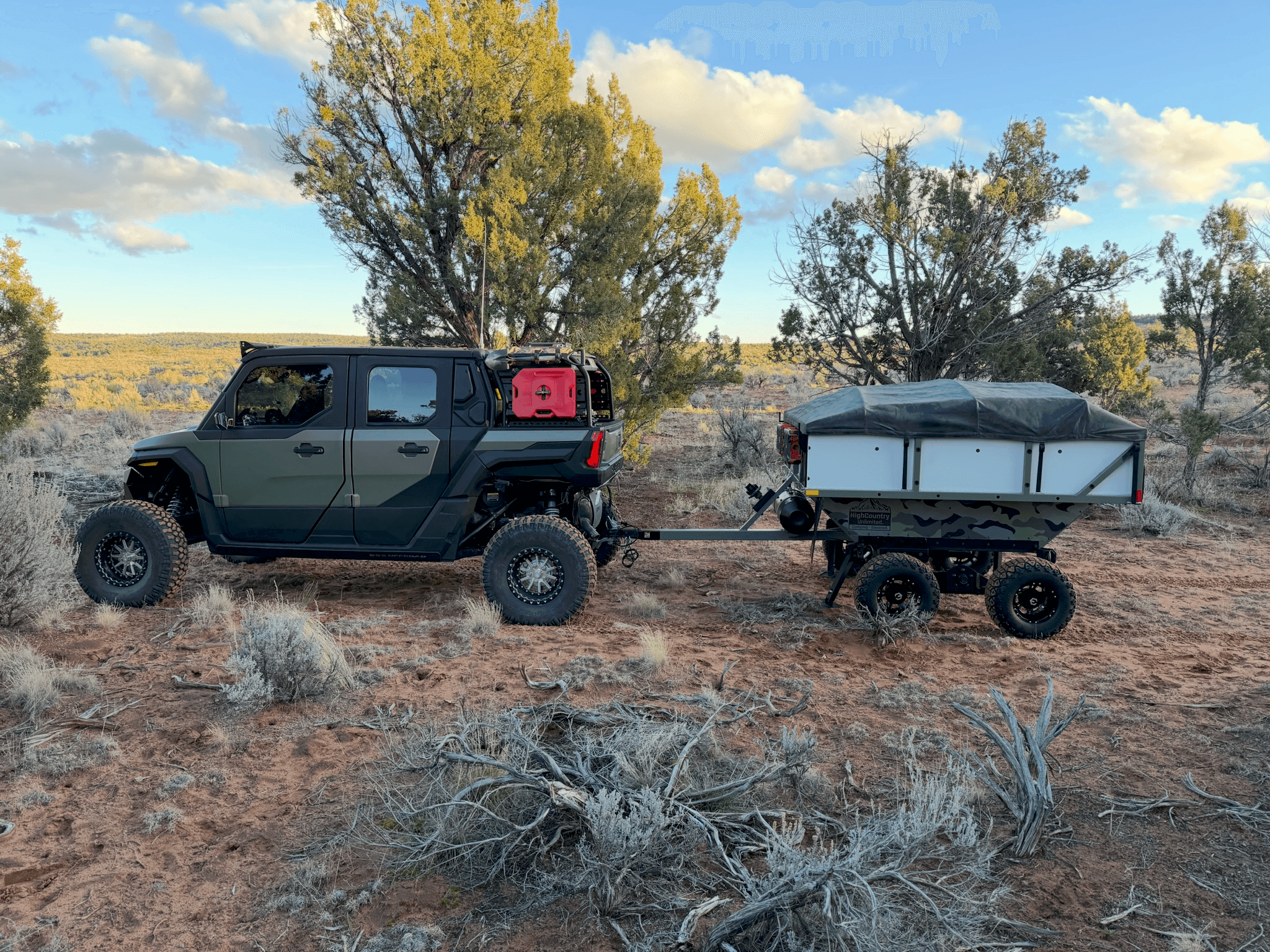 UTV towing a High Country Unlimited camp trailer through desert terrain