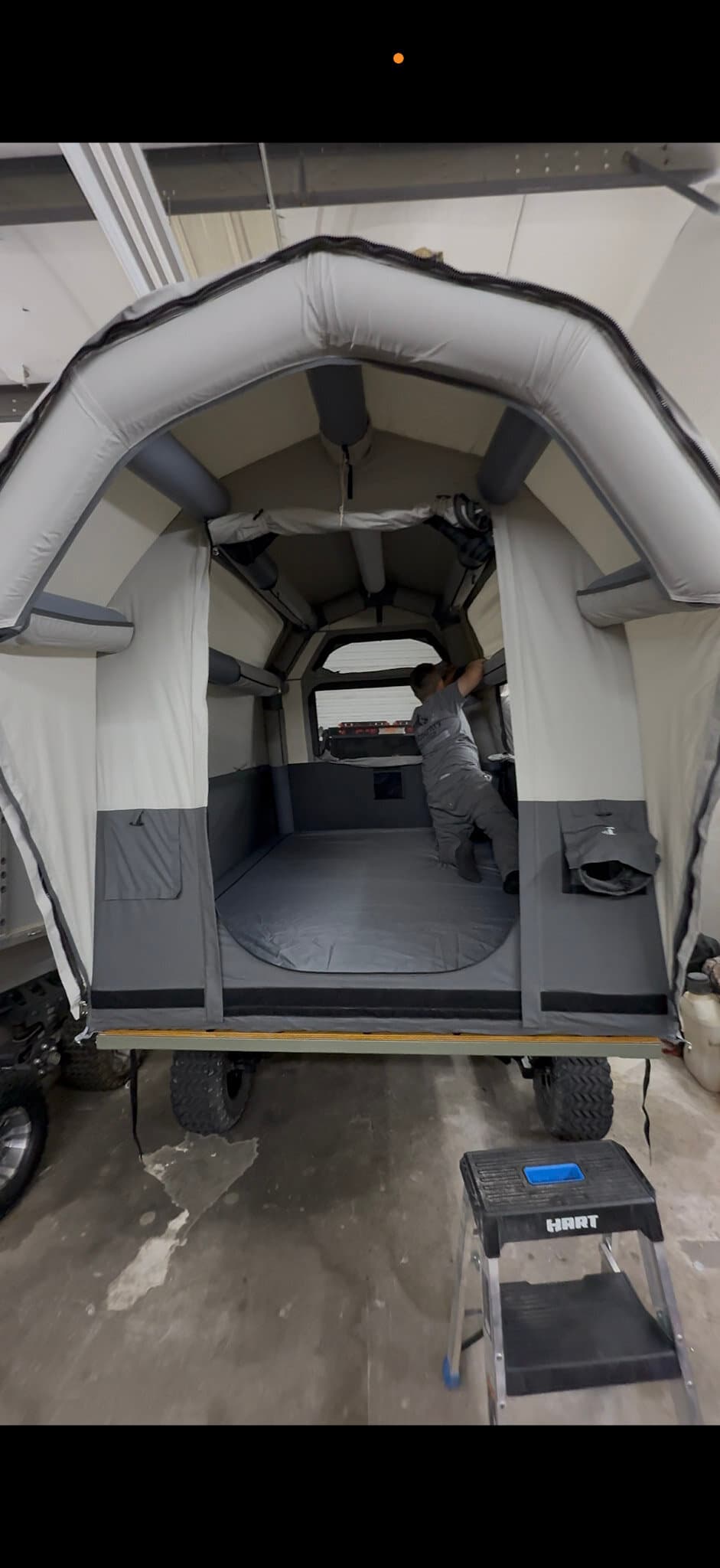 Inside a High Country Unlimited covered wagon camper, where the arched airframe tent gives full standing height over the mattress