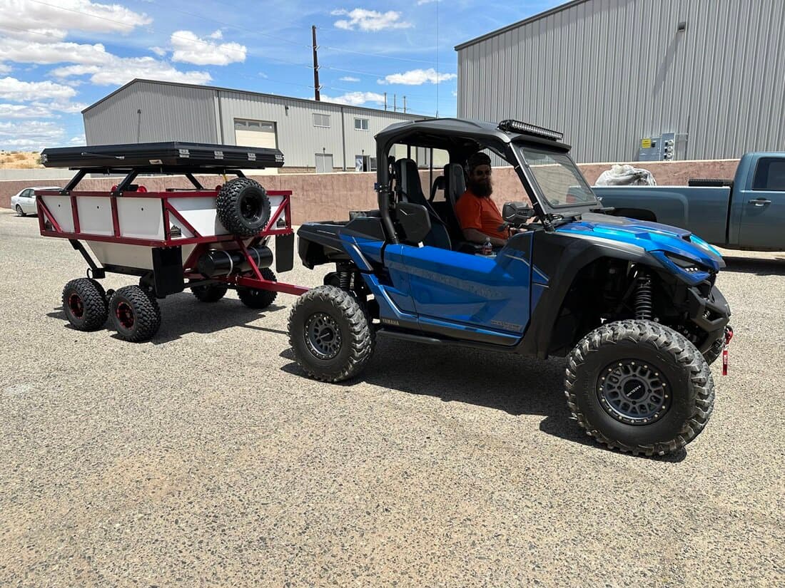 A High Country Unlimited rooftop-tent overland trailer paired with a side-by-side at a remote camp