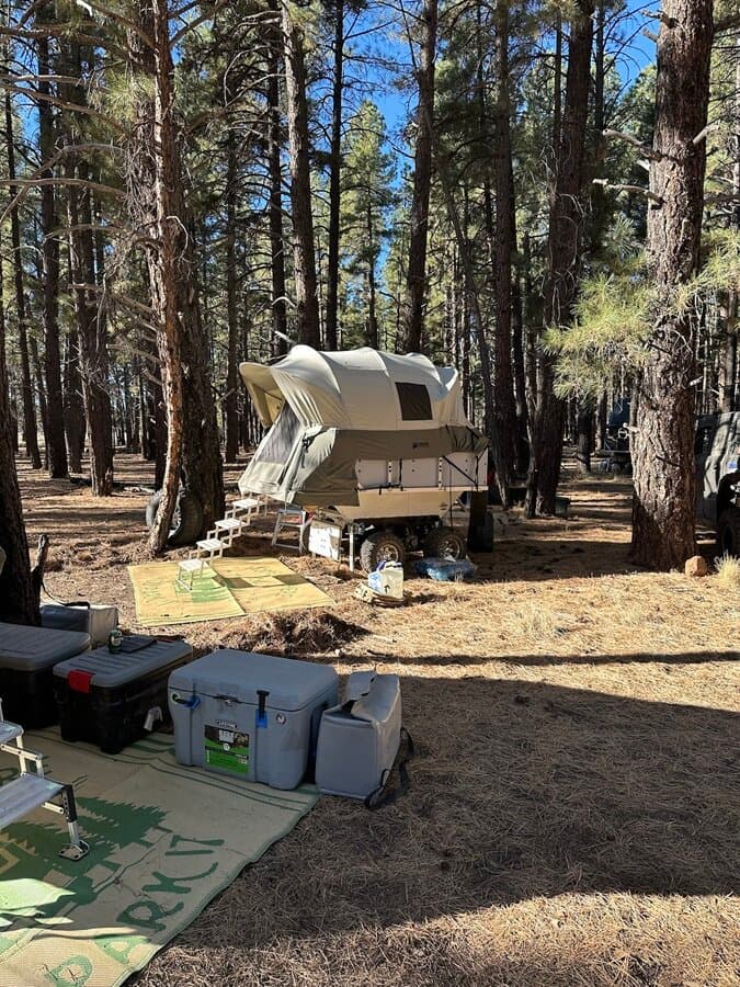 A High Country Unlimited overland camp trailer parked alone among the pines
