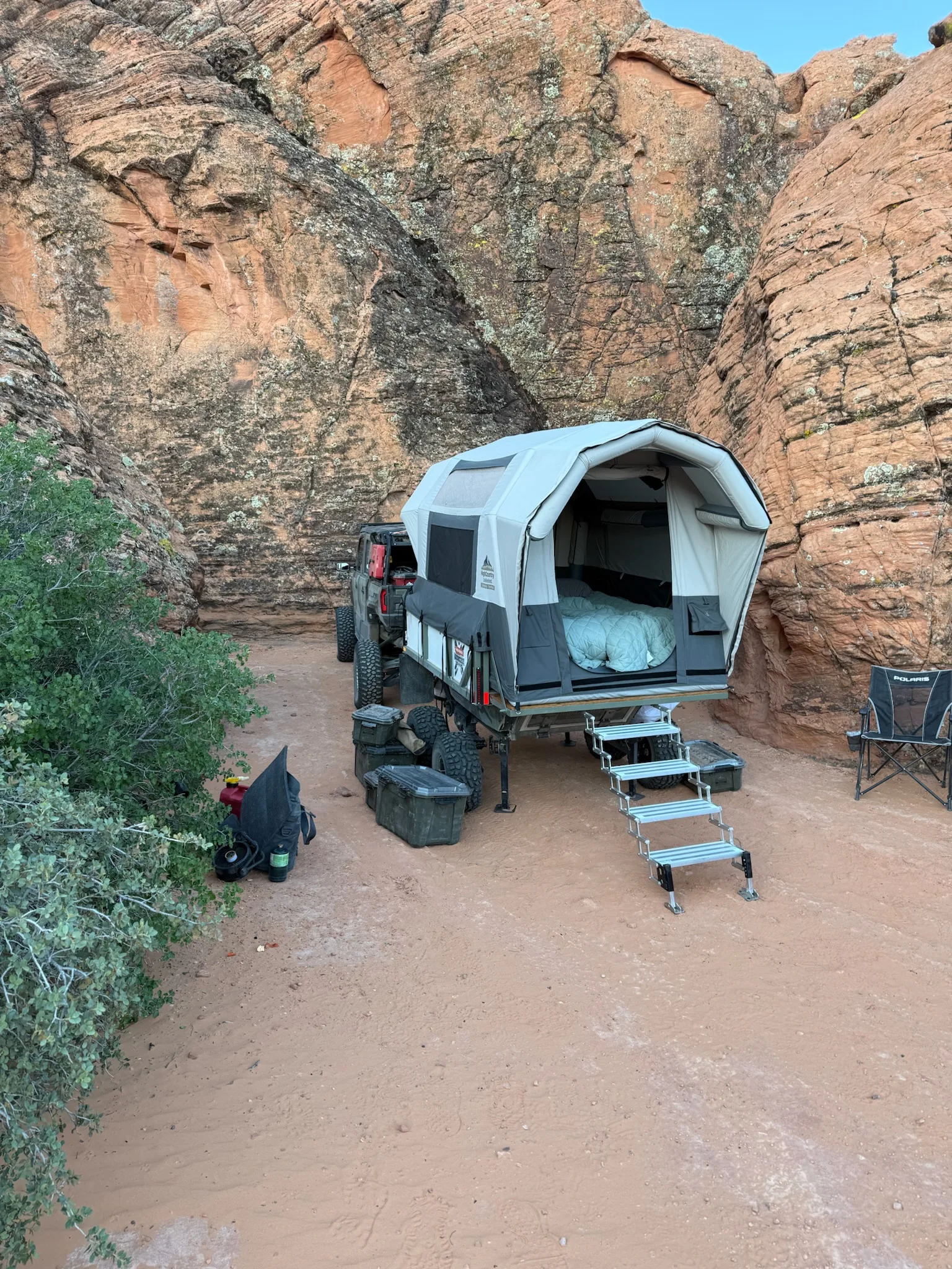 A High Country Unlimited Conestoga Rover camped against a red-rock canyon wall with its airframe tent deployed and entry steps down